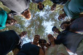 Photo taken from below, from the center of a circle, people looking down toward the camera, smiling